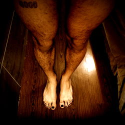 A model showcasing a bold and expressive pose with a tattoo, set against a dimly lit background, evoking a sense of adventure and personal style.