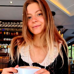 Anni posing with a cup of coffee at a café