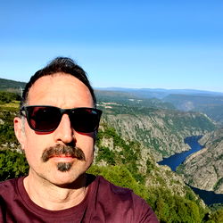 A Man with a Mustache Posing in Front of a Stunning Mountain Landscape