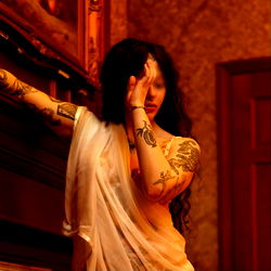 Model posing in a room with antique furniture