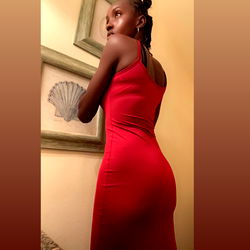 Auburn-haired model in red dress, mid-stride, against wall