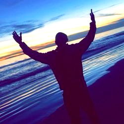 Silhouette of Man Raising Hands in Sunset