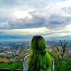 A Tale of Nature's Beauty: A Young Woman with Green Hair Contemplates the City from a High Vantage Point