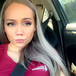Aura, a USA OnlyFans Model in a Maroon Shirt with Blonde Hair and Tattoos, Sitting in a Car