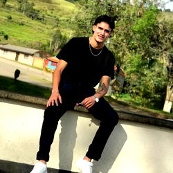 Alejandro Bran, a young adult from Medellín, poses confidently against a serene backdrop. His casual attire suggests a relaxed and informal setting.