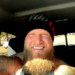 Magnus, a bearded tattooed man in truck taking selfie