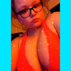 Kelsey, an OnlyFans model, captured in a vibrant, low-light setting