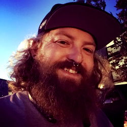 Bearded Man with Glasses and a Hat, Posing for the Camera Outdoors