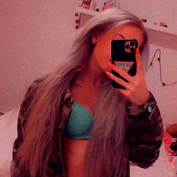 Alvviinn, a model from the Czech Republic with blonde hair, showcasing her style on Instagram. She's known for her long locks and a unique fashion sense. In this photo, she is standing in front of a mirror, capturing her reflection with a phone.