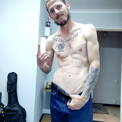 Shirtless Man in Blue Jeans, Tattooed Chest, and Tattoo Arm