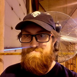 Man in Cap, Glasses and Beard at a Factory