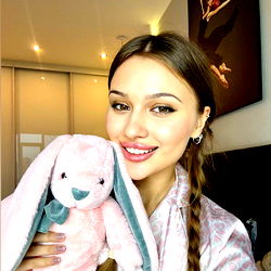 Sonya, a model on OnlyFans, holding a plush toy in a cozy room