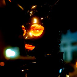 A striking OnlyFans model in a black mask and futuristic costume, set against an urban night scene.