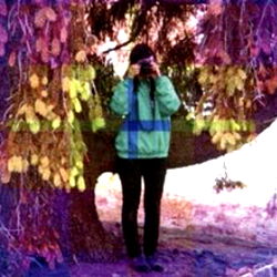 A model photo with a focus on the subject standing under a colorful tree,