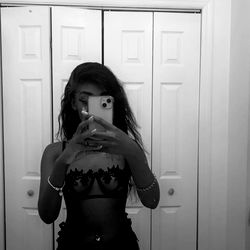 Black and white photograph of a person taking a selfie in front of a mirror