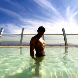 Fit Model in Poolside Setting, Shirtless with Chiseled Abs and Watchful Eye
