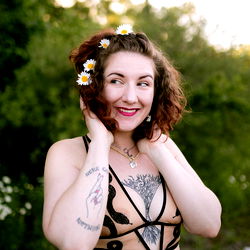 OnlyFans Honey, a boudoir model from Grand Rapids, MI, posing in a candid outdoor photo with a lush background.