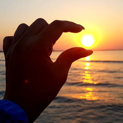 Sunset Silhouette: A Captivating Scene of Sun, Sea and Hand
