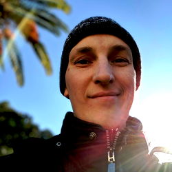 Aleksandar Šeter, smiling in front of a palm tree on a sunny day