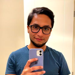 Stylish Man in Glasses, Casually Dressed, Taking a Mirror Selfie