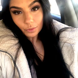 Ann, a young woman with dark hair and a light jacket, posing in a car