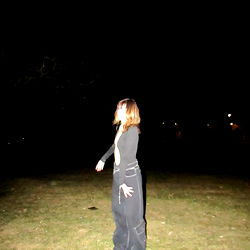 A woman posing in a field at night.