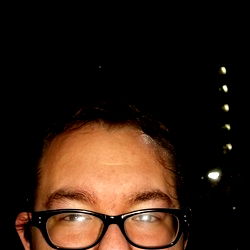 Man with glasses and beard in an outdoor setting at night