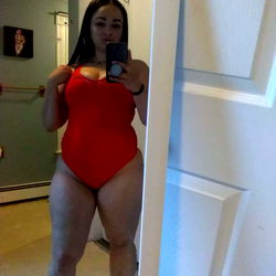 Bella, a New Hampshire OnlyFans Model, Strikes a Confident Pose in Her Red One-Piece Swimsuit