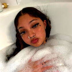 Alora Noelle, a stunning beauty with captivating eyes and a radiant smile. Her hair is styled in loose waves that add to her overall charm.