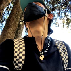 Fashionable individual in a checkered backpack with a face mask, enjoying an outdoor activity