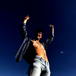 Dante, the OnlyFans Model, Raising His Hands in Excitement Against a Blue Sky Background