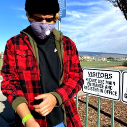A Person in a Mask Standing on the Sidewalk