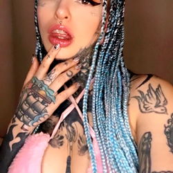 Melissa Rabbit, OnlyFans Model, in Blue Hair and Colorful Outfit, Making a Mouth Gesture