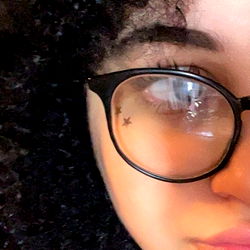 Fashion-forward individual with eye glasses and tattoos, close-up portrait with focus on eyes and eyelashes