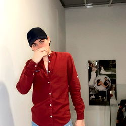 Model in a red shirt standing in an indoor setting