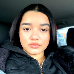 Amber, young woman with a neutral expression in a vehicle.