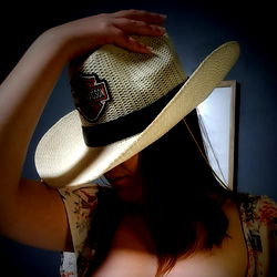 Woman in a cowboy hat tipping it over her shoulder