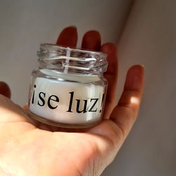 A Human Hand Holding a Jar of Candles with 'Luz' Inscription