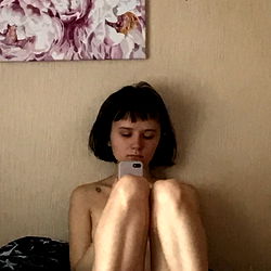 Young Woman with Short Hair Sitting and Looking at a Phone