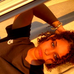 Aicha in a sunny outdoor setting, taking a selfie