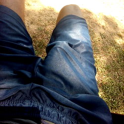 A person lounging outdoors in a pair of blue shorts.