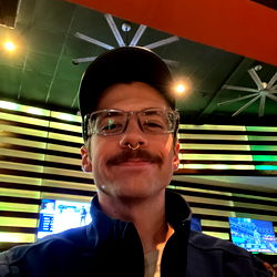 A man in a Boston Bottoms hat, standing confidently with a sports team logo.