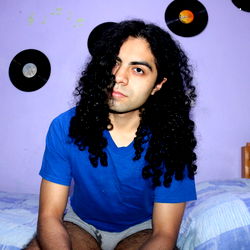 Young Man with Long Hair in Bedroom