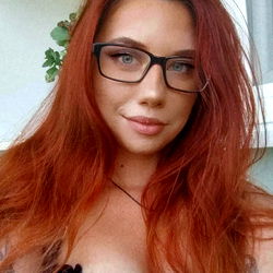 A model with striking red hair and glasses, 29 years old.