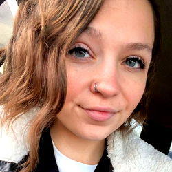 Smiling woman with blue eyes and nose piercing, sharing a casual vibe on her social media.