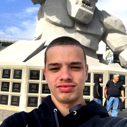 Dylan Cummings in front of the Statue of Superman at a sports stadium