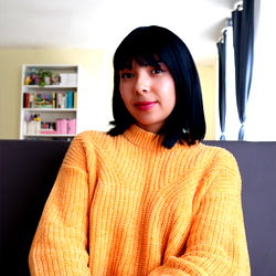 OnlyFans Model ✨Mary✨ poses in a cozy room with a yellow sweater and black pants.