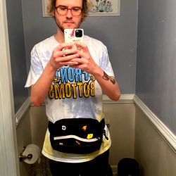 Casually Dressed Man with a Phone in Hand Standing in Front of Mirror