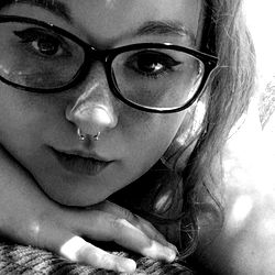 A young adult with glasses, posing for a selfie.