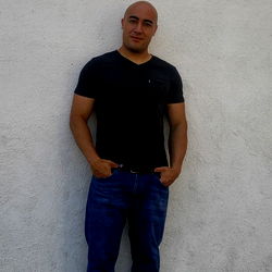 Lostwolf poses confidently against a white wall in Los Angeles.